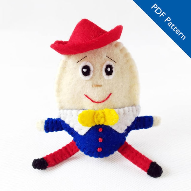 Puede incluir: Mu&ntilde;eca de fieltro hecha a mano que representa a Humpty Dumpty, con un cuerpo en forma de huevo color crema, un sombrero rojo y una chaqueta azul con pajarita amarilla. Las piernas de la mu&ntilde;eca son rojas y los pies negros. El texto "PDF Pattern" est&aacute; en la esquina superior derecha.