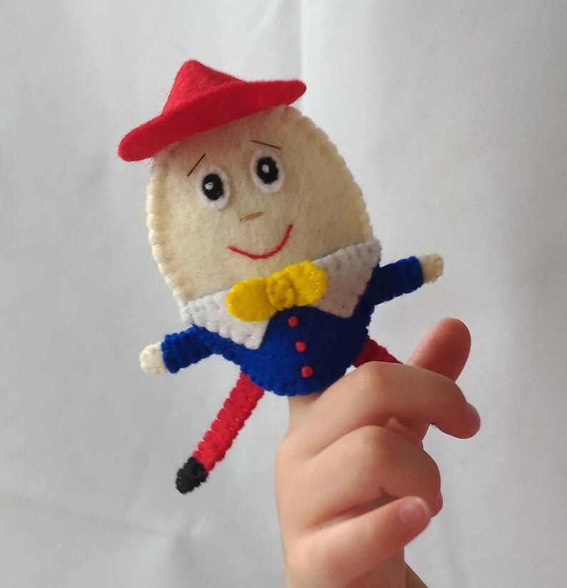 Puede incluir: T&iacute;tere de dedo de Humpty Dumpty hecho a mano. El t&iacute;tere de fieltro presenta un cuerpo en forma de huevo de color crema, un sombrero rojo, una chaqueta azul y piernas rojas. Tiene una pajarita amarilla y una cara sonriente.