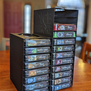 K&ouml;nnte beinhalten: Schwarzer Plastik-Organizer mit durchsichtigen Schubladen zum Aufbewahren von Dice Throne-Spielkarten. Jede Schublade ist mit dem Namen eines Charakters beschriftet, wie z. B. Treant, Santa und Barbarian.