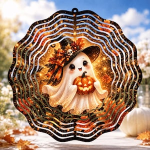 Peut inclure: Un carillon à vent circulaire en métal présentant une illustration centrale d'un fantôme blanc portant un chapeau de sorcière noir avec un crâne et des feuilles d'automne orange, tenant une citrouille lumineuse dans un cadre festonné noir.