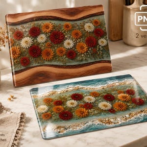 May include: Two rectangular boards featuring floral designs. One board has a natural wood edge with a center inlay of red, orange, and white flowers in resin. The other board displays a beach scene with flowers, sand, and shells in resin.