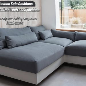 May include: A grey sectional sofa with multiple cushions and pillows. The sofa has a white base and is near a large window. Text on the image reads "Custom Sofa Cushions" and "Customized Thickened Cushion". The cushions are described as "zippered, removable, easy care, hand-made."