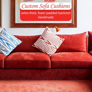Op de afbeelding: Een rode bank met sierkussens. Eén kussen heeft een blauw-wit patroon, de andere rood-wit. De tekst in de afbeelding luidt "Custom Sofa Cushions extra thick, foam padded backrest handmade."
