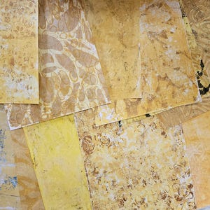 Op de afbeelding: Een verzameling gele, gepatroneerde vellen papier met verschillende texturen en ontwerpen. Het papier is lichtgeel met een subtiele bruine tint.