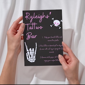 May include: A black card with pink text that says "Ryleigh's Tattwo Bar". The card has instructions for a tattoo party activity. The instructions include picking a tattoo, placing it on your skin, and covering it with a wet rag for 30 seconds.