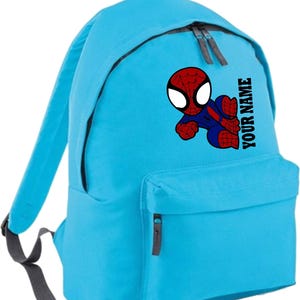 May include: A light blue backpack featuring a graphic of Spider-Man in red and blue. The backpack has a front pocket and two zippered compartments. The text "YOUR NAME" is printed vertically on the side.
