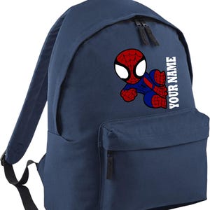 May include: A navy blue backpack featuring a Spiderman graphic. The Spiderman image is red, blue, and white. The backpack has a front pocket, two zippers, and the text "YOUR NAME" in white.