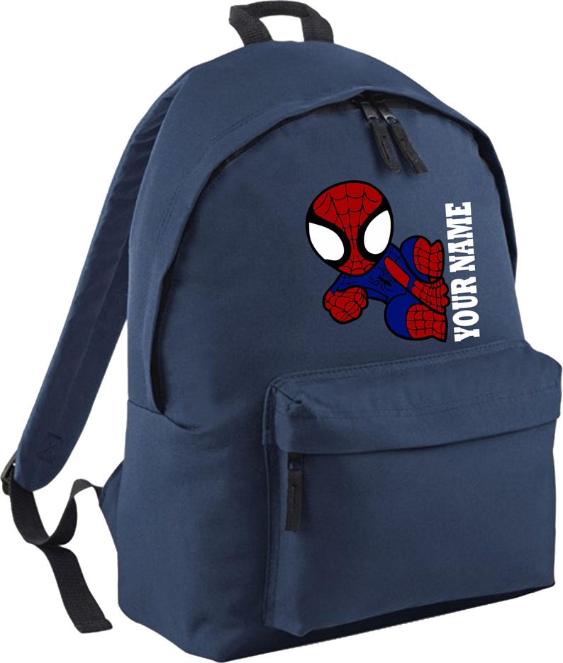 May include: A navy blue backpack featuring a Spiderman graphic. The Spiderman image is red, blue, and white. The backpack has a front pocket, two zippers, and the text "YOUR NAME" in white.