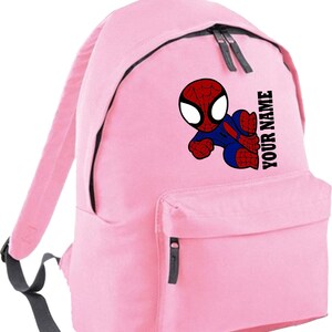 May include: Pink backpack featuring a cartoon Spider-Man graphic in red, blue, and black. The backpack has a front pocket, black zippers, and the text "YOUR NAME" printed vertically. The straps and top handle are gray.
