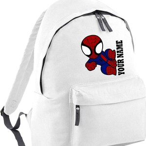 May include: White backpack featuring a cartoon Spider-Man graphic in red, blue, and black. The backpack has a front pocket, a top handle, and the text "YOUR NAME" printed vertically on the side. The straps and zippers are gray.