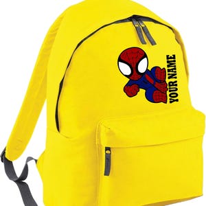 May include: Yellow backpack featuring a cartoon Spider-Man graphic. The backpack has a front pocket, two side straps, and the text "YOUR NAME" printed vertically on the side. The backpack has black zippers and a gray handle.