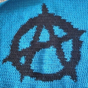 May include: A blue crocheted square with a black anarchy symbol in the center.