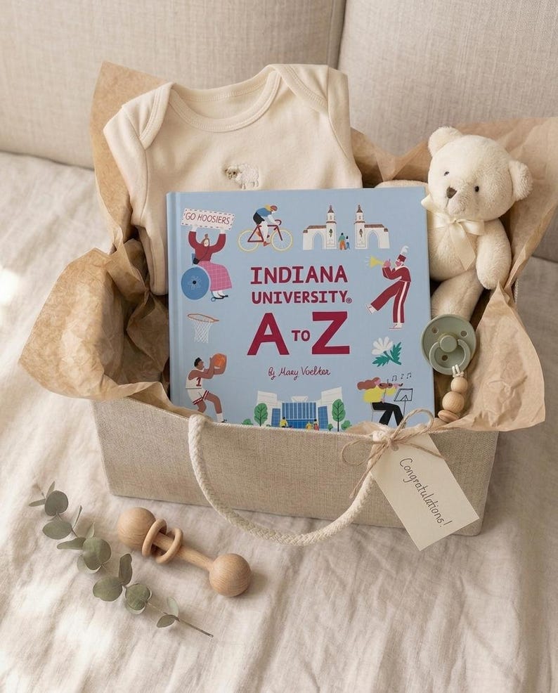 Puede incluir: Una caja de regalo que contiene un body de beb&eacute; color crema, un libro azul claro Indiana University A to Z, un peque&ntilde;o oso de peluche crema, un chupete verde salvia con cuentas de madera y un sonajero de madera, con una etiqueta que dice Congratulations!