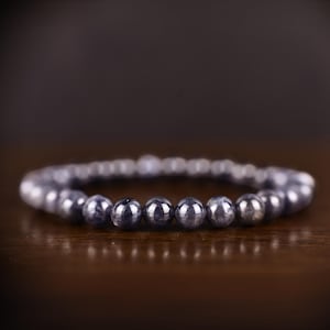 May include: A dark blue gemstone bracelet with round beads. The bracelet is made of natural stones and is a beautiful piece of jewelry.