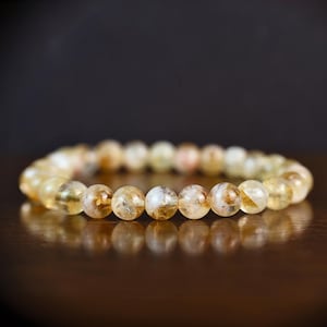 Op de afbeelding: Een armband gemaakt van ronde, doorschijnende, gele en witte kralen.