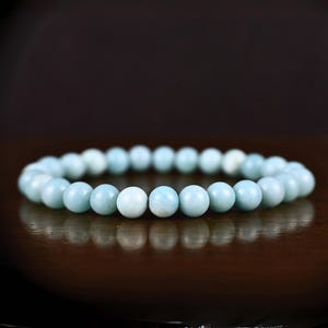 May include: A light blue gemstone bracelet made of round beads.