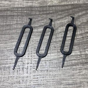 May include: Three black plastic tools with a hook on one end and a loop on the other. The tools are designed to help remove small objects from tight spaces.