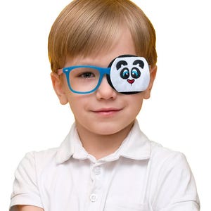May include: Blue eyeglasses featuring a removable fabric eye patch attachment. The patch is white with a black and white embroidered panda face design, including black ears, blue eyes, and a small red heart-shaped nose, covering the left lens.
