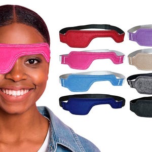 May include: A collection of fabric eye patches with elastic headbands, available in red, purple, bright pink, beige, light blue, dark blue, grey, and black. Each patch features a contoured shape designed to cover one eye with stitched edges.