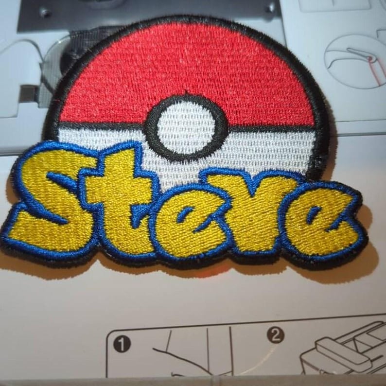 May include: An embroidered patch featuring a circular red and white ball design with a central black and white circle. Below the ball, the name Steve is stitched in yellow thread with a thick blue border, creating a bold, colorful graphic.
