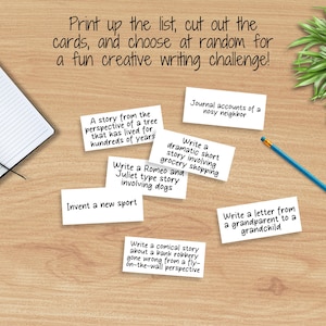 May include: A set of white cards with creative writing prompts, such as "Write a Romeo and Juliet type story involving dogs" and "Journal accounts of a nosy neighbor". The cards are on a wooden surface with a notebook and a pencil.