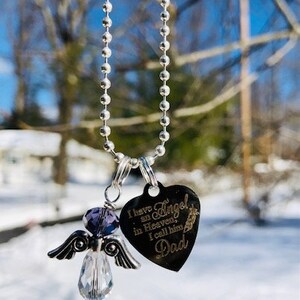 May include: A silver chain necklace with a heart-shaped pendant that reads "I have an Angel in Heaven, I call him Dad". The pendant is attached to a small angel charm with a purple crystal.