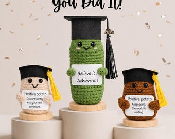 Könnte beinhalten: Drei gehäkelte Figuren, eine Gurke und zwei Kartoffeln, tragen Abschlusskappen. Die Gurke hält ein Schild mit der Aufschrift "Believe it! Achieve it!". Die Kartoffeln haben Schilder mit "Positive potato" und motivierenden Botschaften. Der Text "You Did It!" steht oben.