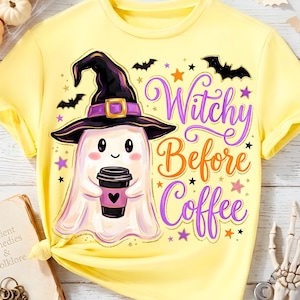 Può includere: Una t-shirt giallo pallido con la grafica di un fantasma bianco che indossa un cappello da strega viola e tiene in mano una tazza di caffè nera. Il testo "Witchy Before Coffee" è scritto in viola e arancione, circondato da pipistrelli neri.