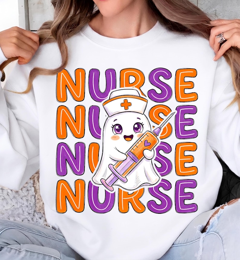 May include: A white sweatshirt featuring a repeating graphic of the word NURSE in orange and purple block letters. In the center, a cartoon ghost wearing a nurse cap holds a large syringe filled with orange liquid and a small purple heart.