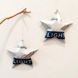 May include: Two white paper star ornaments with blue text. The top star has the text "Bud Light" and the bottom star has the text "Budweiser Light".