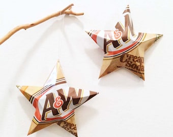 May include: Two brown and white paper stars with the A&W Root Beer logo and the text "Cream Soda" hanging from a branch.