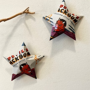 May include: Two white star-shaped ornaments with a red devil illustration and the text "Devil's Backbone Belgian Style Tripel".