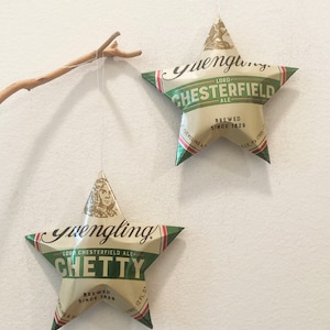 May include: Two green and gold star-shaped ornaments made from Yuengling beer cans. The top ornament reads "Yuengling Lord Chesterfield Ale Brewed Since 1829". The bottom ornament reads "Yuengling Lord Chesterfield Ale Chetty Brewed Since 1829".