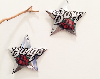 May include: Two silver foil stars with the word "Bargs" printed on them. The stars are hanging from a white wall.