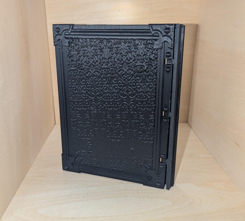 May include: A black, decorative, hinged box with a detailed, embossed pattern on the front.