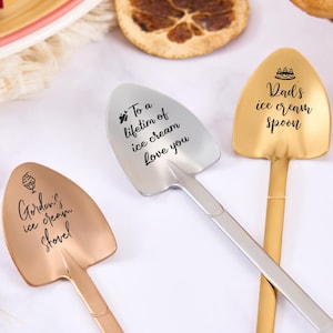 May include: Three ice cream spoons with shovel-shaped heads. One is gold with "Dad's ice cream spoon" text, another is silver with "To a lifetime of ice cream Love you" text, and the third is rose gold with "Gordon's ice cream shovel" text.