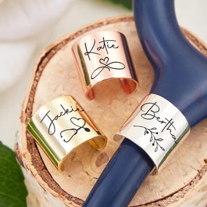 May include: Three personalized stethoscope charms with different names and designs. The charms are made of metal and have a polished finish. The names on the charms are "Katie", "Jackie", and "Bertha".