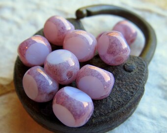 May include: A collection of small, round, pink and white glass beads with a speckled texture. The beads are arranged on a rusty metal padlock.