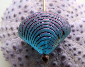 May include: A blue glass bead with a textured, iridescent finish. The bead is shaped like a seashell and has a gold-coloured wire attached to it.