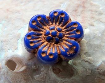 May include: A blue glass flower bead with gold accents. The bead has a five-petal flower design with a raised center.