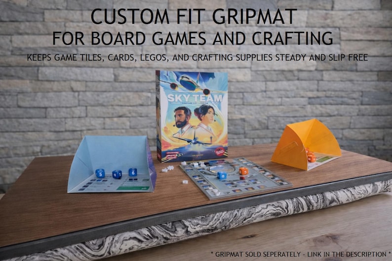 May include: A wooden board game surface with the text "CUSTOM FIT GRIPMAT FOR BOARD GAMES AND CRAFTING". The image shows a board game box, dice, and game pieces. The surface is designed to keep game tiles, cards, and crafting supplies steady.