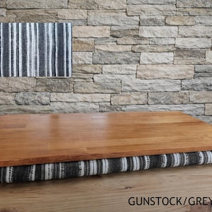May include: A wooden laptop desk with a striped cushion base. The desk has a light brown wooden surface and a cushion with vertical stripes in shades of gray and white. The text "GUNSTOCK/GREY STRIPES" is visible at the bottom.