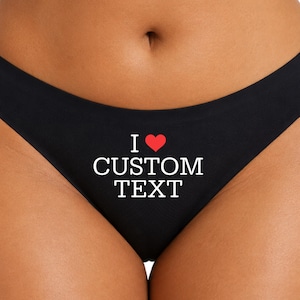 May include: Black underwear featuring the white text "I" followed by a red heart symbol and the words "CUSTOM TEXT" printed in a bold, serif font centered on the front of the garment. The design is simple, clean, and clearly legible.