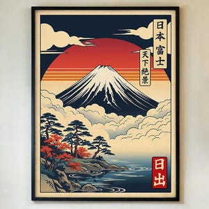 May include: Framed art print featuring a Japanese landscape with Mount Fuji. The artwork showcases a red sun, blue water, and stylized trees. Japanese text is visible in the upper right and lower right corners. The print is framed in a black frame.