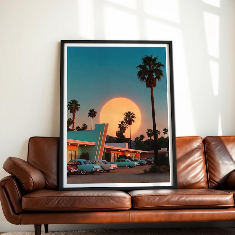 May include: A framed print depicting a retro motel scene at sunset. The image features palm trees, vintage cars, and a large sun. The motel has a teal and white color scheme, and the sky is a gradient of blue and orange.