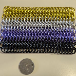 May include: A chainmail flag with yellow, white, purple, and black rings. The flag is about the size of a UK 20 pence coin.