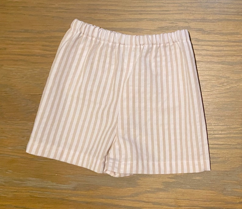 May include: Beige and white striped cotton shorts with an elastic waistband.