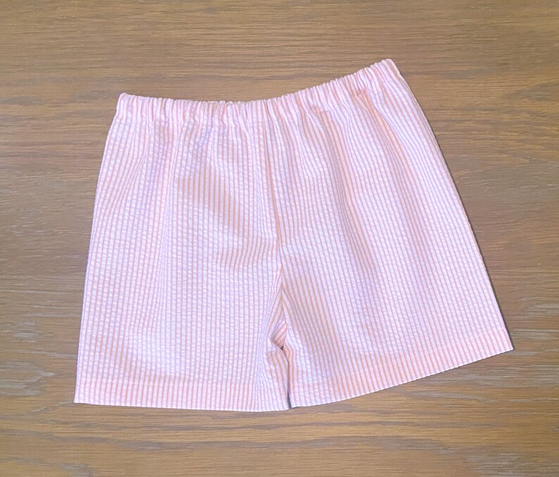 May include: Pink and white striped shorts with a white elastic waistband.