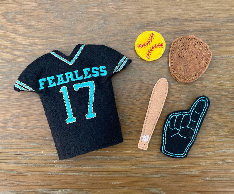 May include: A black felt jersey with the word "Fearless" and the number "17" embroidered in turquoise blue.  There are also felt baseball-themed accessories, including a baseball, a bat, and a foam finger.