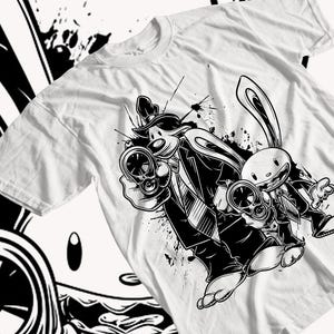 Può includere: Illustrazione in bianco e nero di un cane e un coniglio che indossano abiti e tengono pistole. L'immagine è su una maglietta bianca.